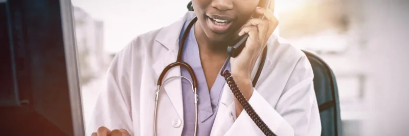 Benefits of telephony for healthcare: Female doctor on phone while using computer